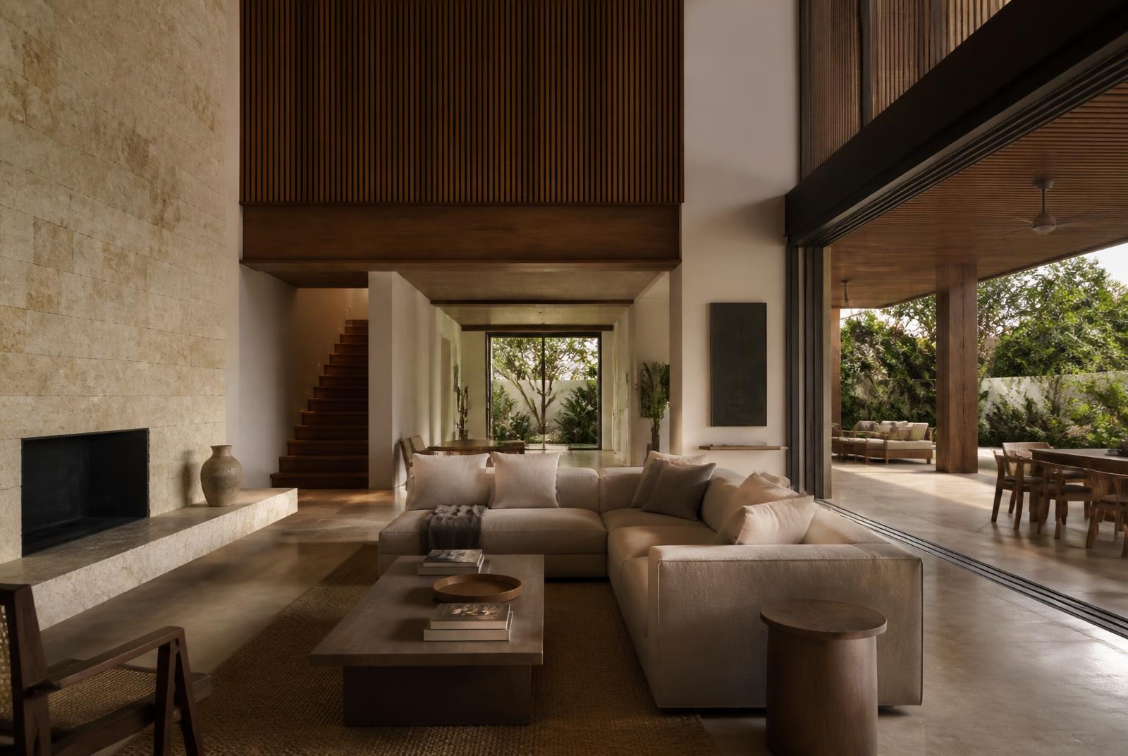 Double-height living room of a Costa Rican residence, warm timber and limestone in soft side light.